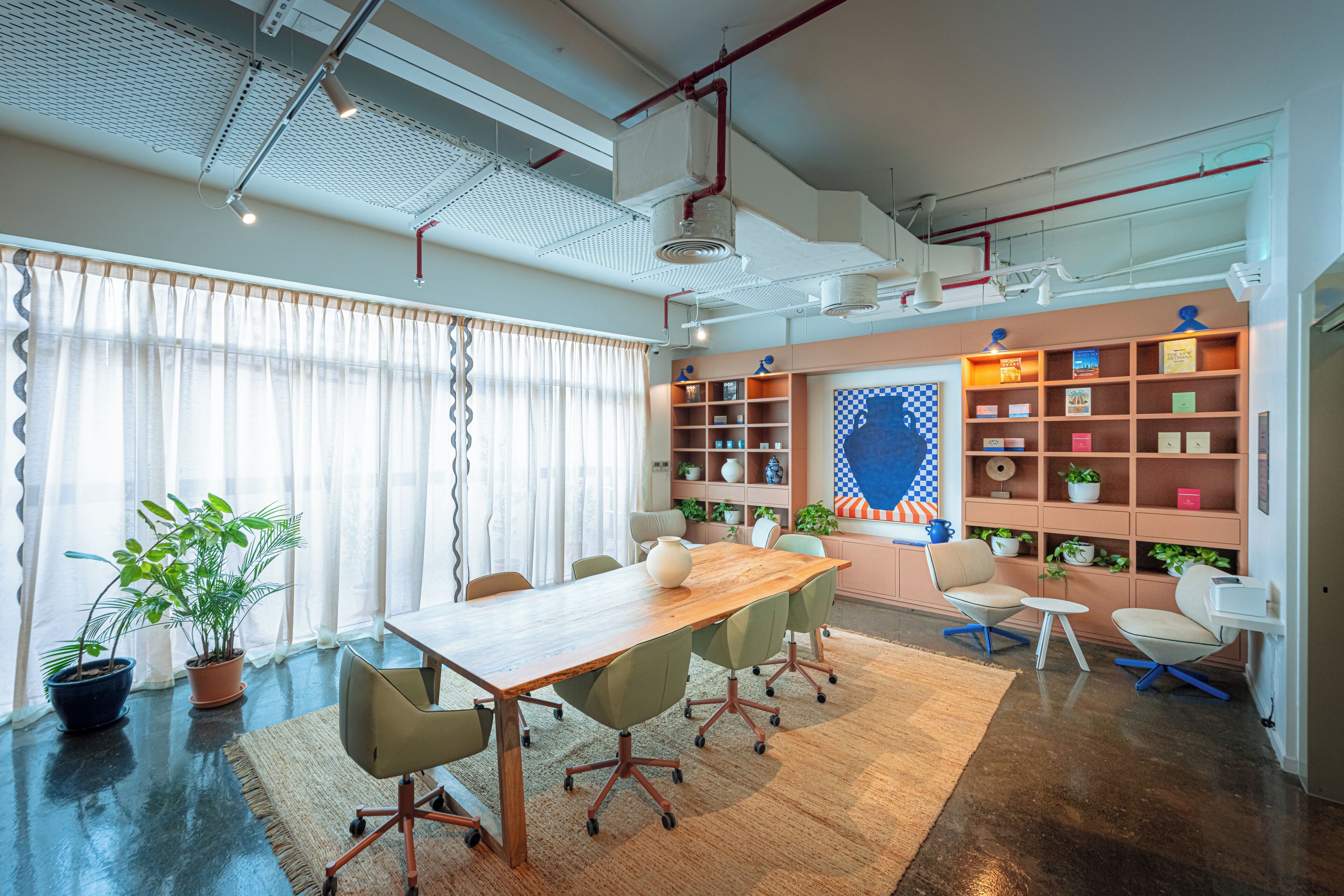 Une salle de réunion moderne, dotée d’une table en bois, de chaises de bureau, d’une bibliothèque et de plantes en pot.