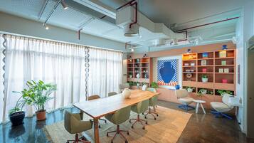 Une salle de réunion moderne, dotée d’une table en bois, de chaises de bureau, d’une bibliothèque et de plantes en pot.