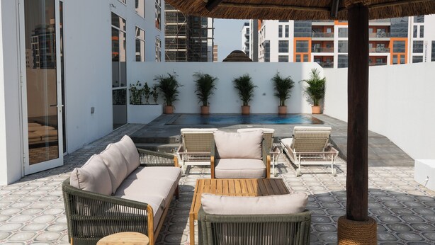 Une terrasse sur le toit, aménagée avec des meubles en osier, une piscine et des plantes en pot.