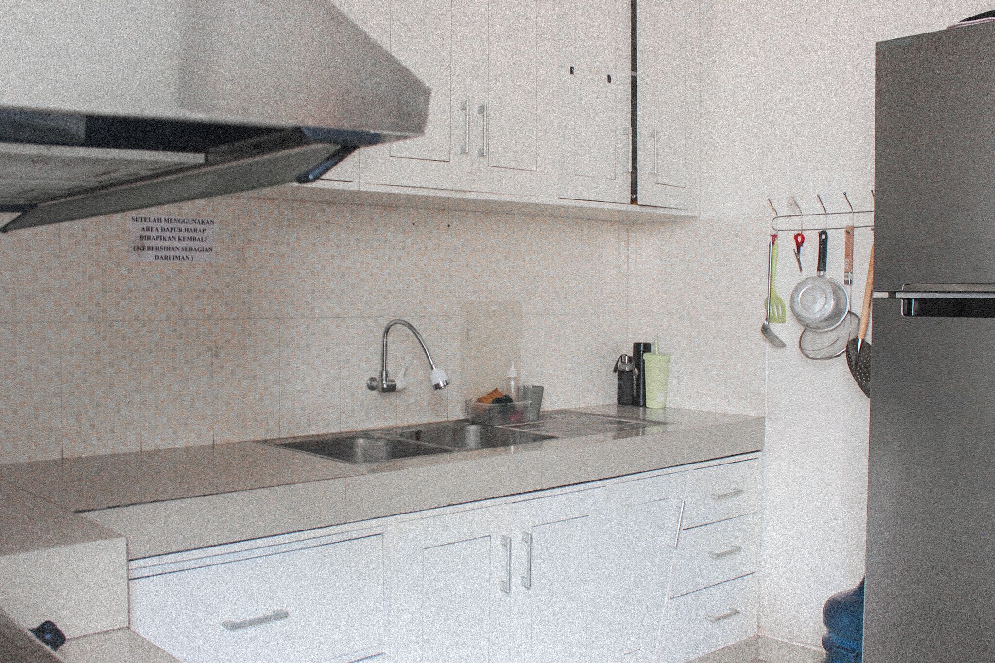 A kitchen with white cabinets, a stainless steel sink, and a range hood.