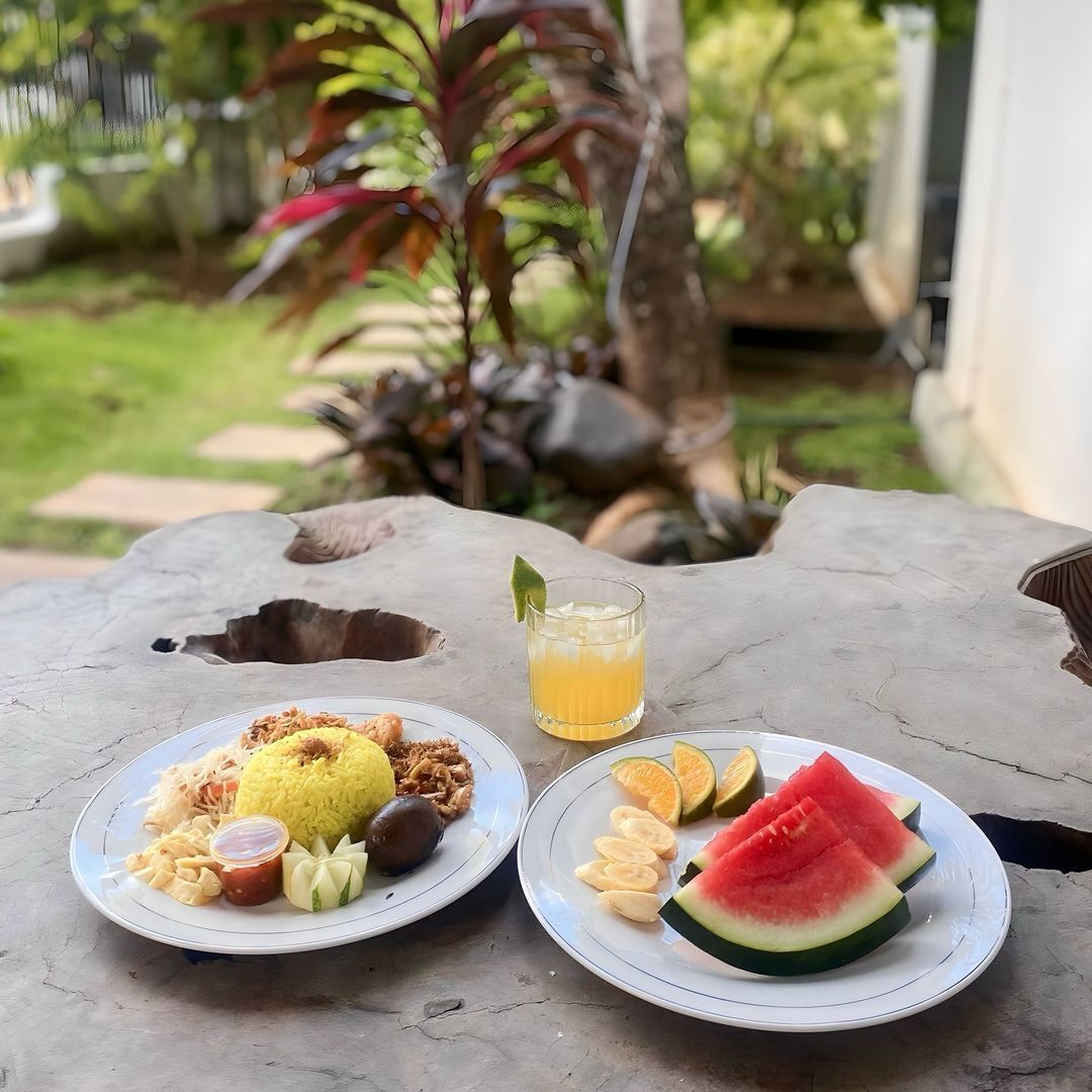 Dos platos de comida y un vaso de jugo sobre una mesa al aire libre.