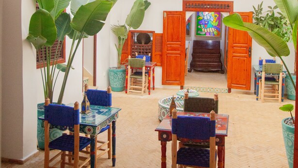 A spacious courtyard with a wooden staircase leading to an upper level, surrounded by potted plants and traditional furniture. - Riad Authentique, à Proximité de la Mer et de Tous les Sites à Visiter à Rabat (RABAT)