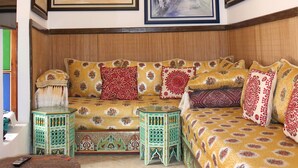 A room with a wooden ceiling, a bed with patterned bedding, a green side table, and framed artwork on the walls. - Riad Authentique, à Proximité de la Mer et de Tous les Sites à Visiter à Rabat (RABAT)