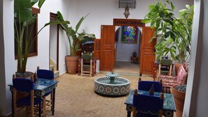 A courtyard with a fountain, potted plants, and traditional wooden furniture. - Riad Authentique, à Proximité de la Mer et de Tous les Sites à Visiter à Rabat (RABAT)