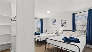 Une chambre avec deux lits simples, une armoire et une fenêtre avec des stores.
