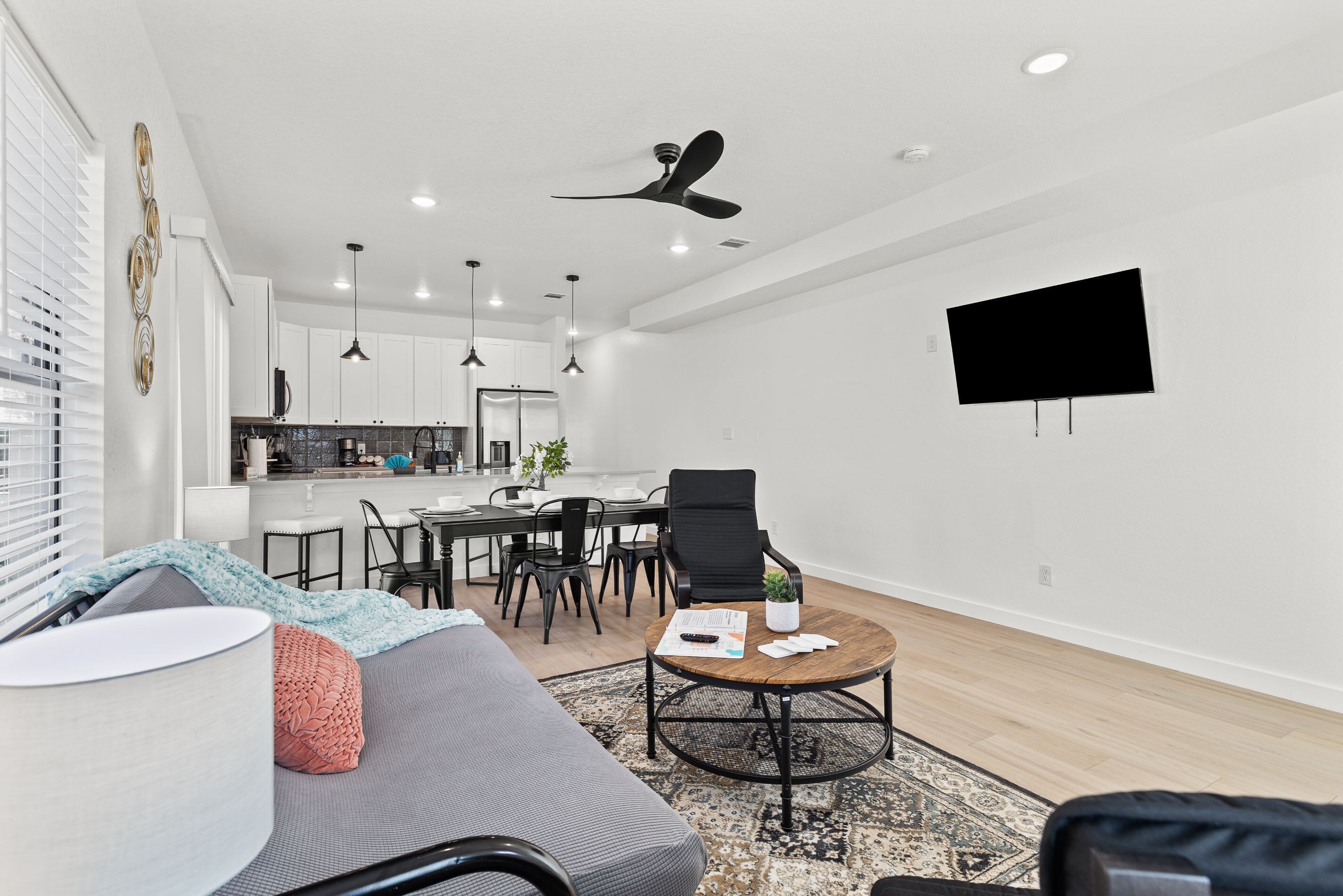 A modern living room with a gray sofa, a coffee table, and a dining area with a black chair and a table.