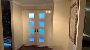 Ein Flur mit einer Doppeltür, die Kassetten aus Sandstrahlglas hat, einem gerahmten Bild an der Wand und einem Holzboden.