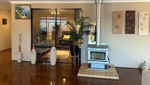 Ein Wohnzimmer mit Kaminofen, Glastür zu einem anderen Raum und dekorativen Vasen.