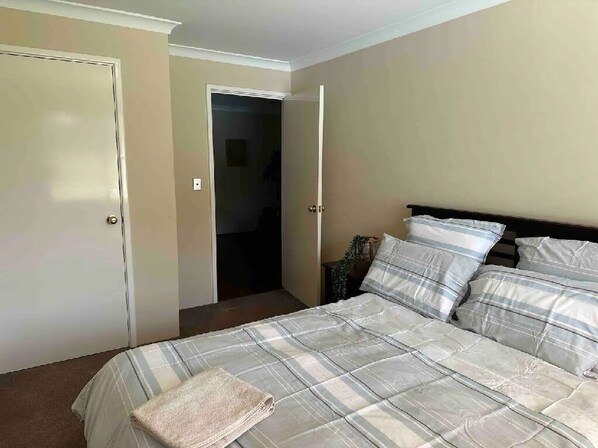 A bedroom with a bed, a nightstand, and a door leading to another room. - Country Oasis on Evans Street
Entire home in Collie, Australia (Collie)