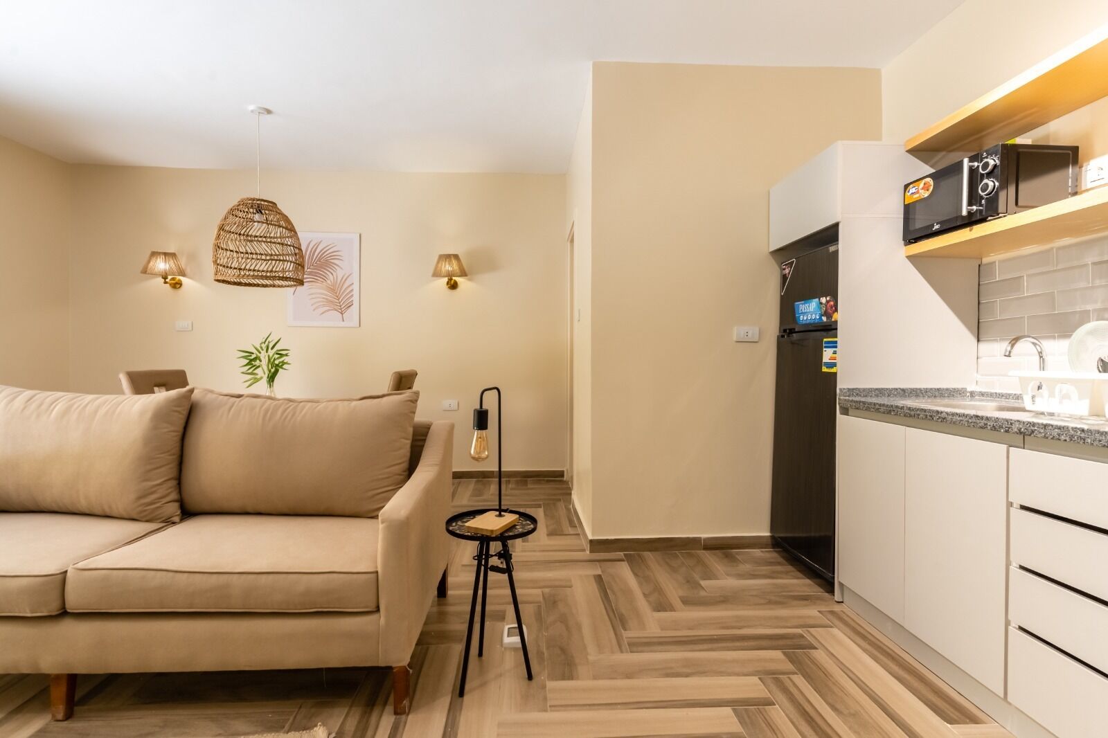 Un soggiorno moderno con un divano beige, un tavolino e una lampada a sospensione.