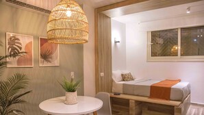 A compact room with a bed, a round dining table with chairs, a hanging light fixture, and wall art. - Bird Nest Near Arkan Plaza  (Sheikh Zayed City)