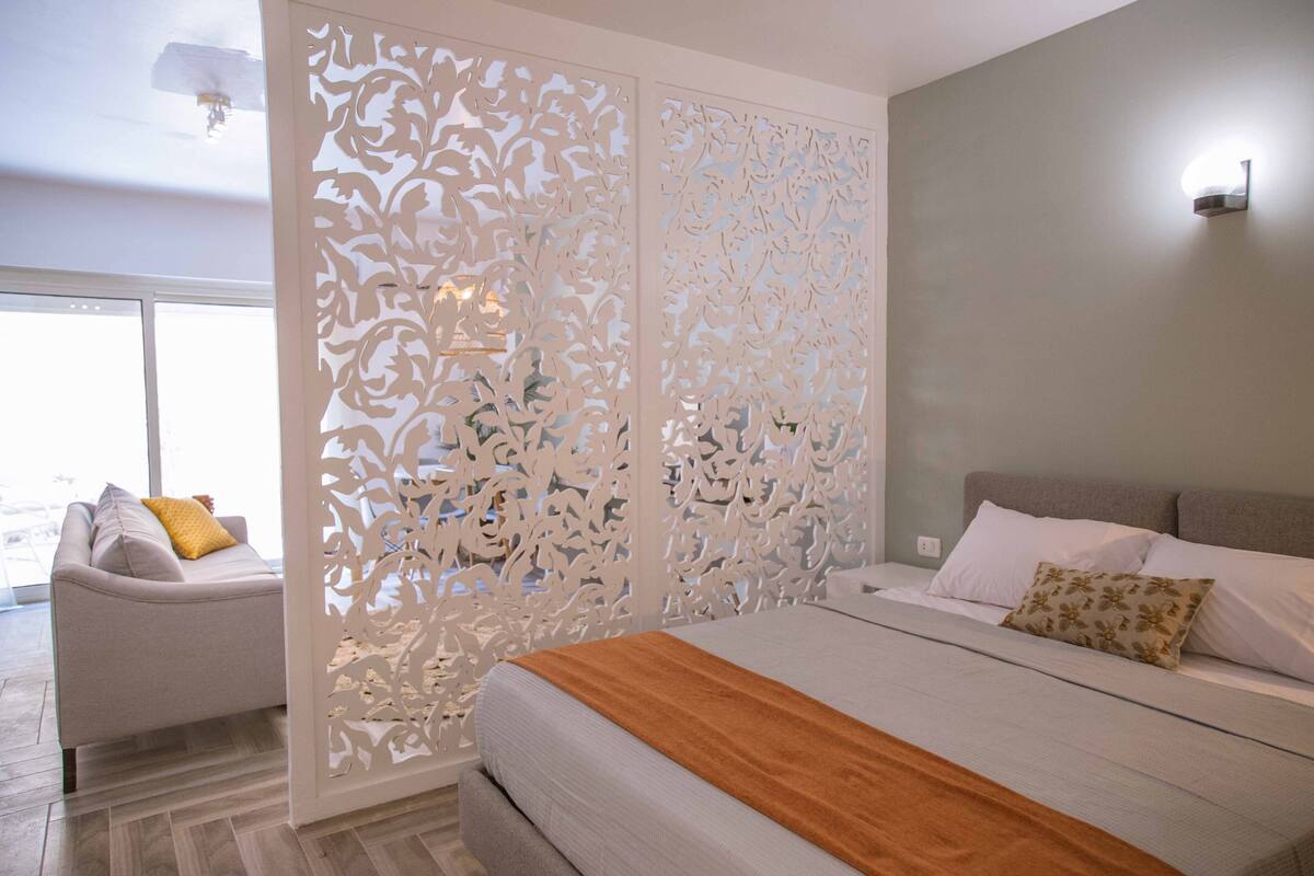 Une chambre à coucher comprenant un lit, un canapé et un élément de séparation décoratif.
