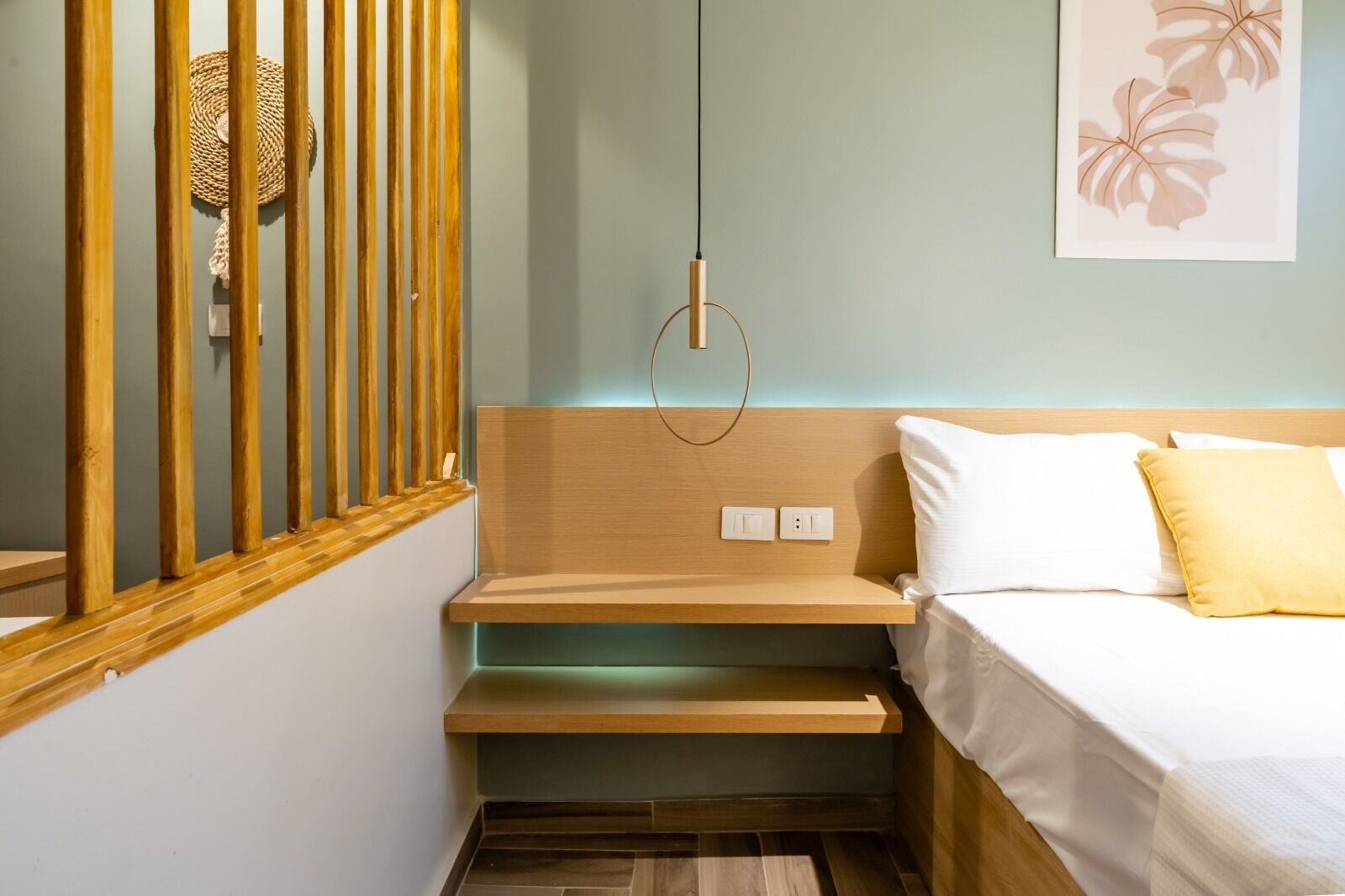 A compact bedroom with a wooden headboard, a bedside table, and a bed with white and yellow pillows.