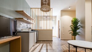 A modern kitchen with wooden flooring, a dining area with a round table, and a large potted plant. - Bird Nest Near Arkan Plaza  (Sheikh Zayed City)