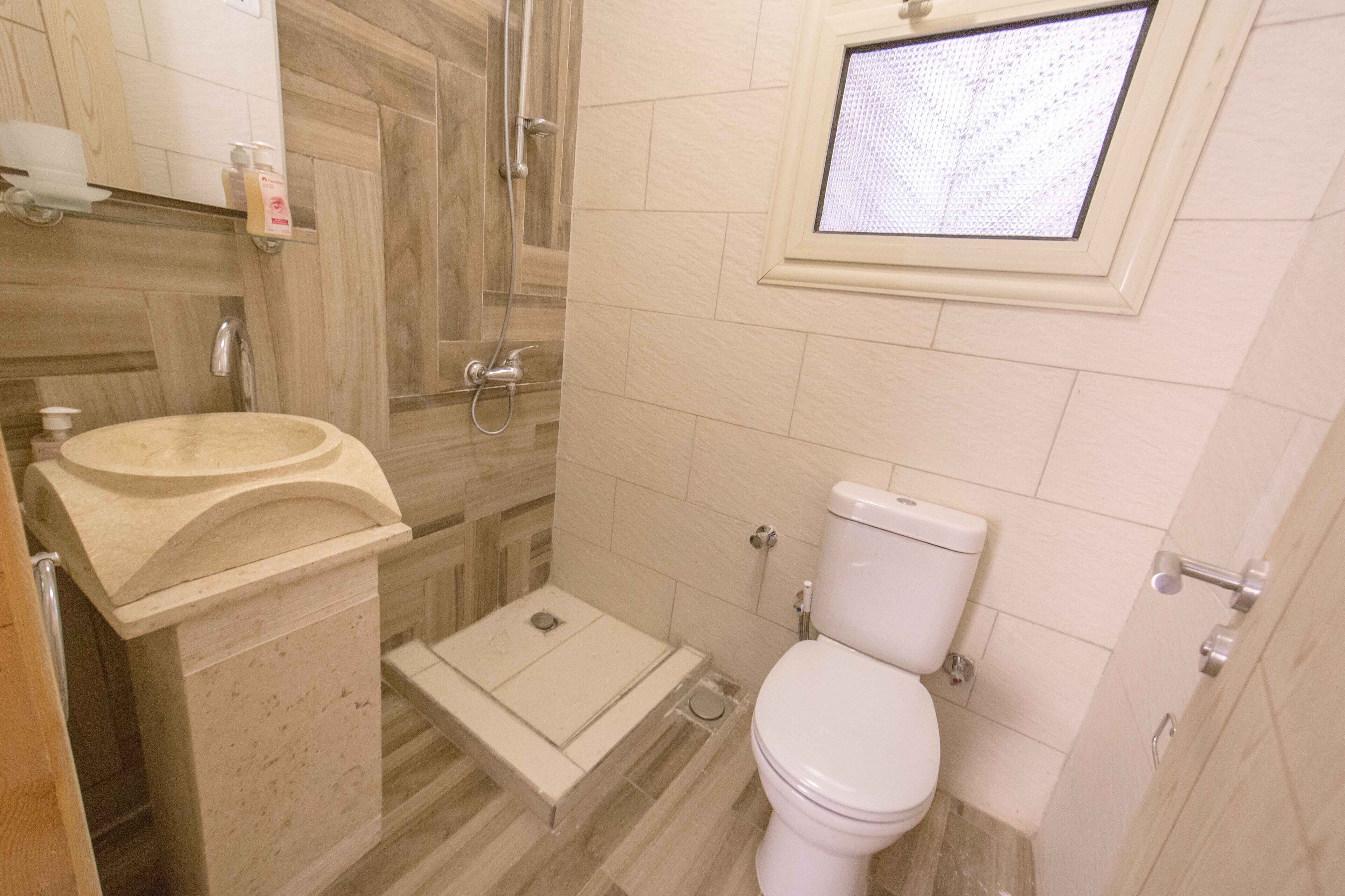 A bathroom with a marble sink, a toilet, and a shower.