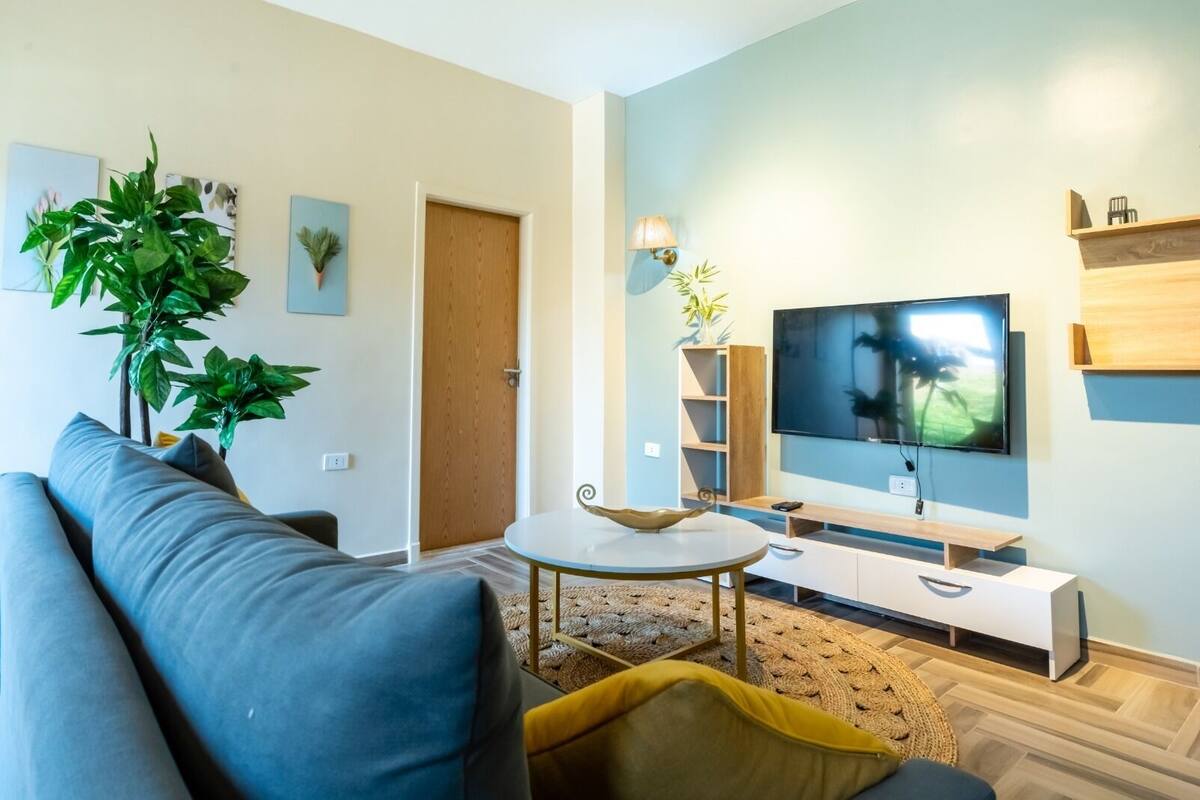 Un salon moderne avec un canapé, une table basse, un téléviseur et une bibliothèque.