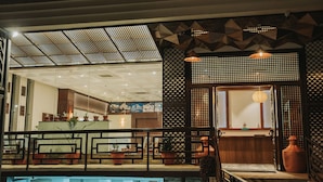 Un moderno vestíbulo de hotel con mostrador de recepción, zona de estar y piscina.