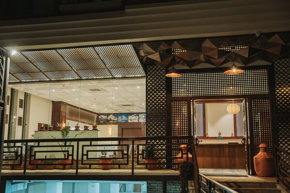 A modern hotel lobby with a reception desk, seating area, and a pool.