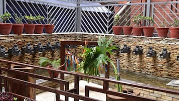 Une cour intérieure avec un mur en pierre, une petite fontaine et des plantes en pot.