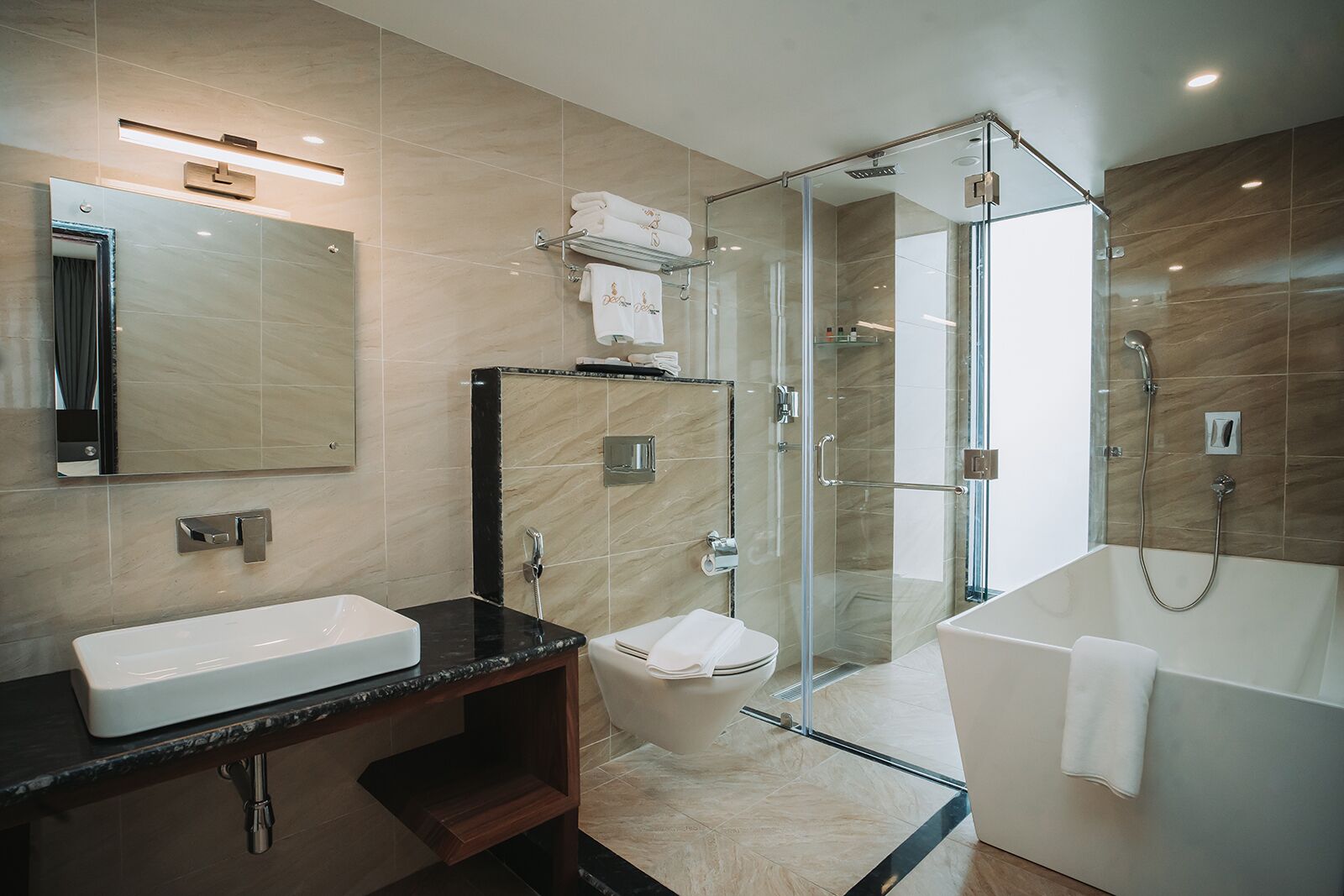 A modern bathroom with a glass-enclosed shower, a standalone bathtub, a vanity with a sink, and a toilet.