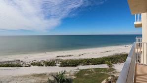 A beach view from a balcony overlooking a sandy beach with a clear sky. - Beachfront EBTC 804A w/ Million $ View! Bargain Price! Pool! Tennis! (Fort Myers Beach)