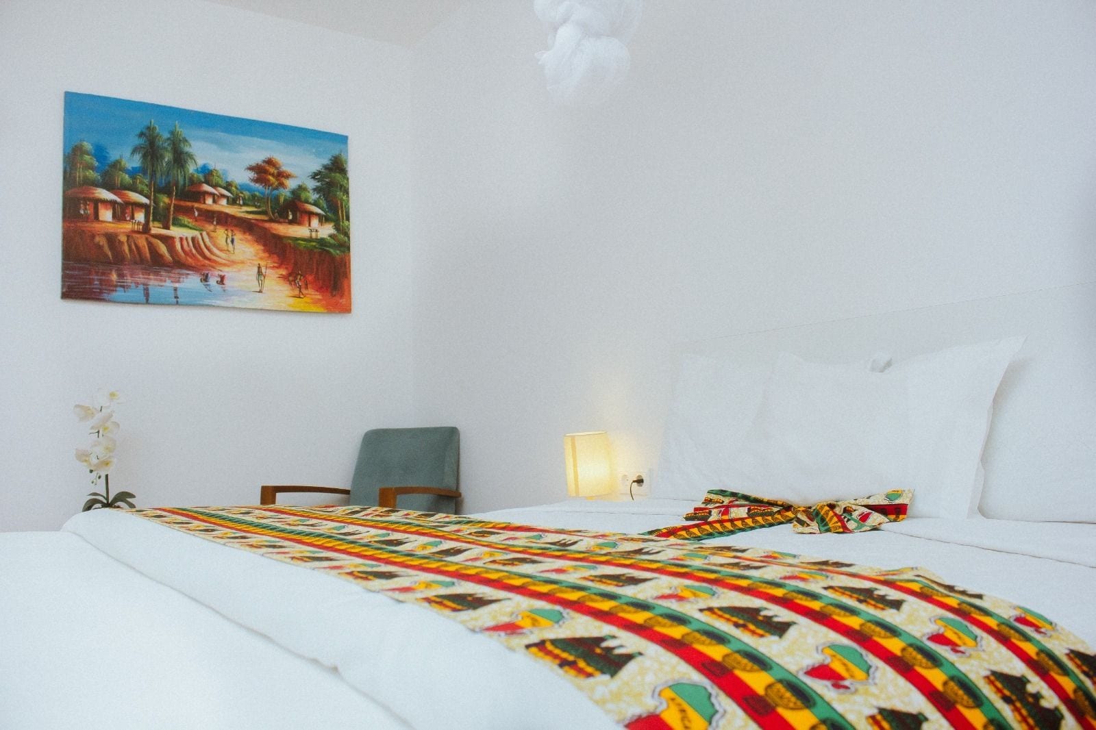 Une chambre d’hôtel avec un lit, une chaise, un tableau et une lampe.