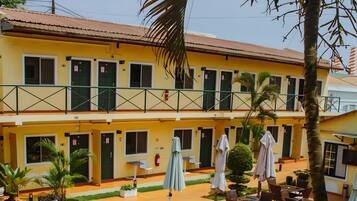 A hotel with a swimming pool, outdoor seating, and a two-story building with balconies.