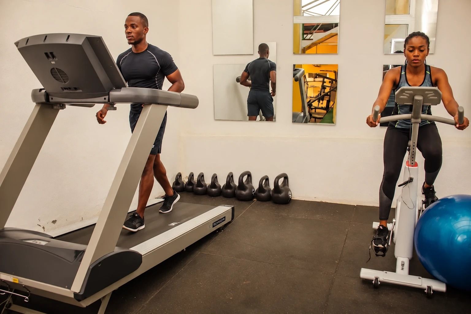 A gym with treadmills, exercise bikes, and kettlebells.