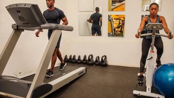 A gym with treadmills, exercise bikes, and kettlebells.