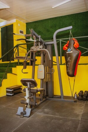 A gym with a punching bag, exercise equipment, and dumbbells.