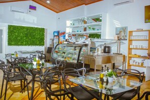 A café with a glass display case, seating area, and shelves with items.