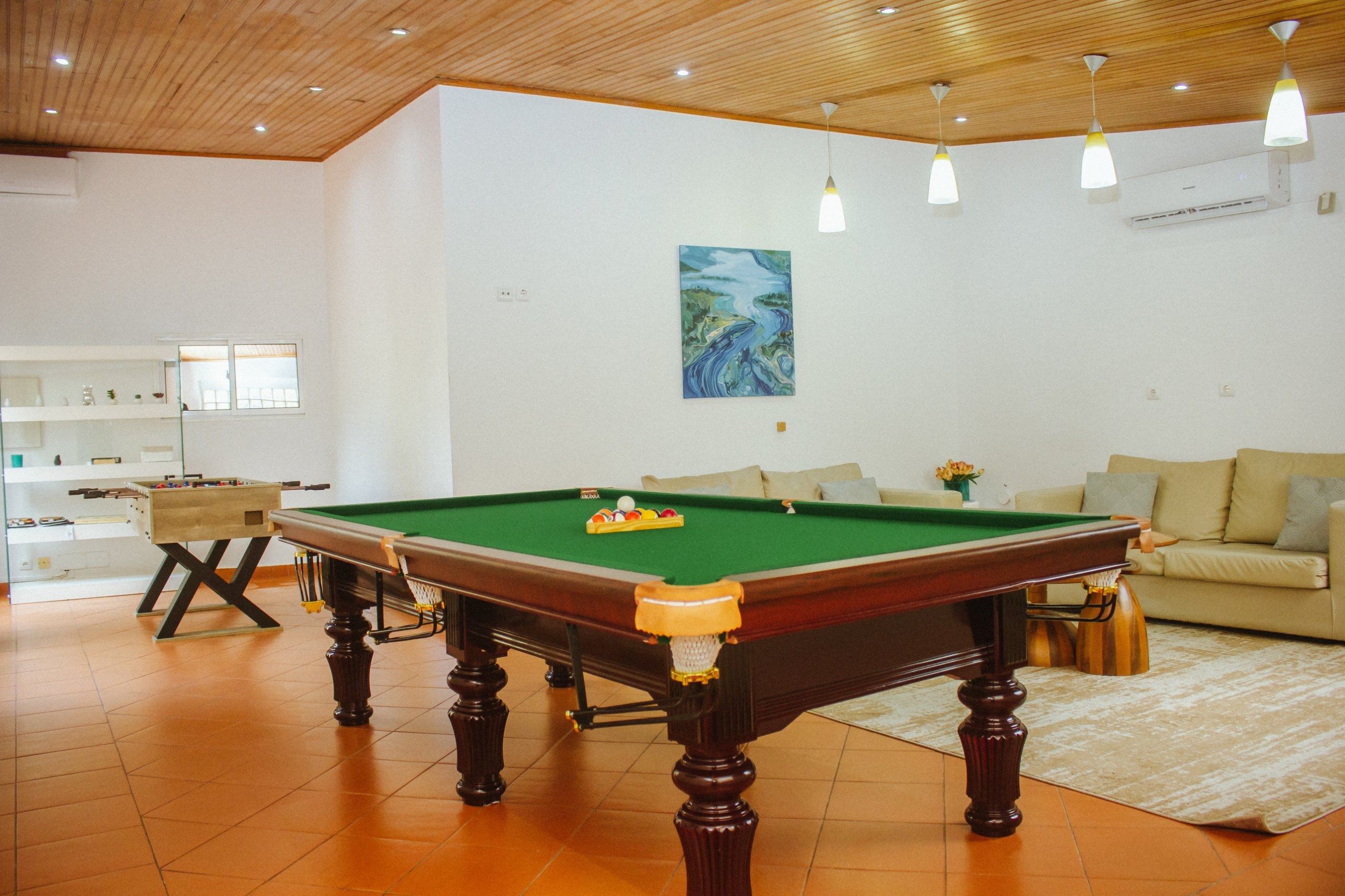 A room with a pool table, a sofa, and a painting on the wall.