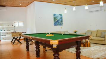 A room with a pool table, a sofa, and a painting on the wall.