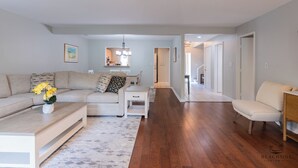 A spacious living room with a sofa, a coffee table, and a dining area with a chandelier.