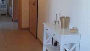 Un pasillo con una consola blanca, una puerta y espejos decorativos en la pared.