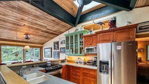 A modern kitchen with wooden cabinets, a stainless steel refrigerator, and a large island with a sink.