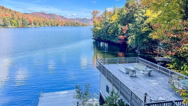 A lakeside deck with a view of a calm lake and autumn foliage.