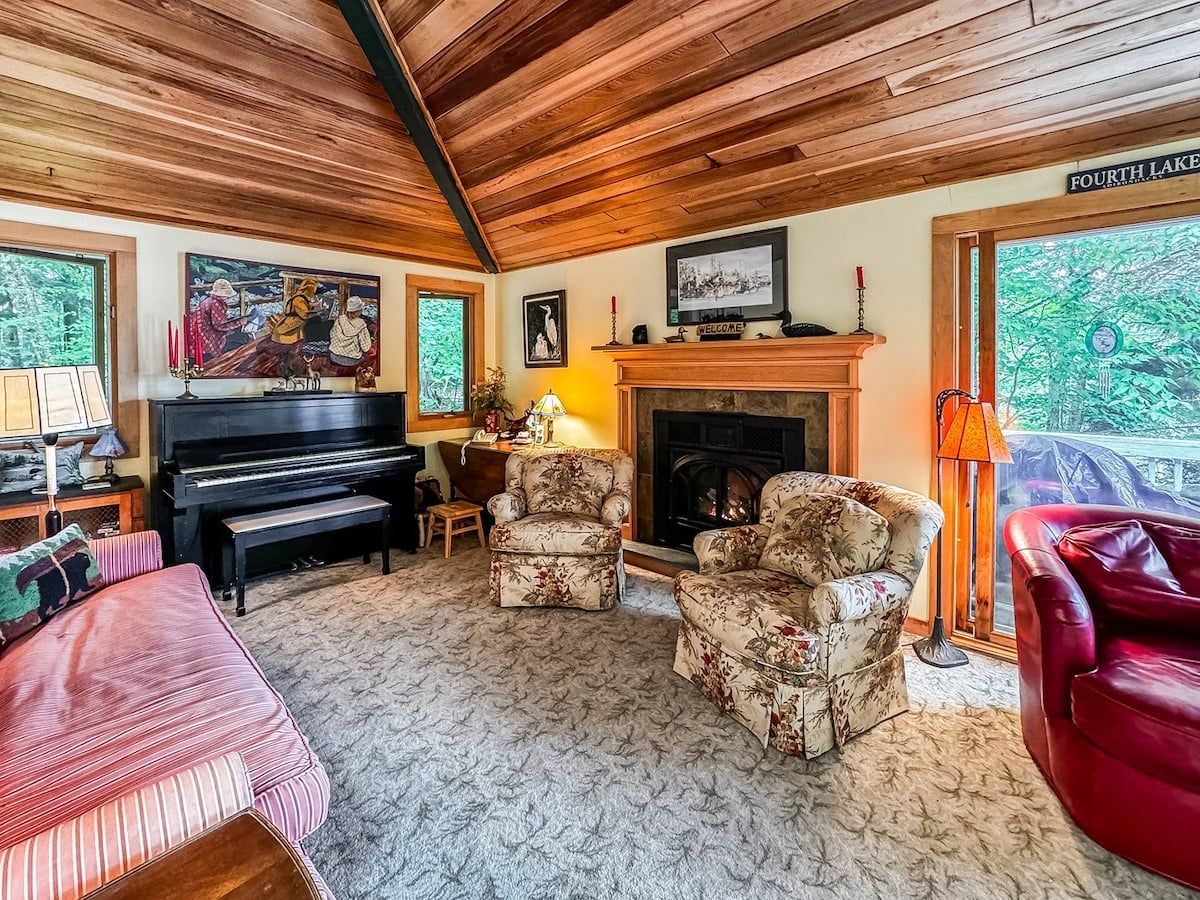 Una sala de estar acogedora con chimenea, un piano y asientos cómodos.
