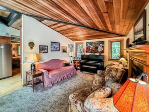 Una sala de estar acogedora con un piano, un sofá, una mesa de centro y una chimenea.