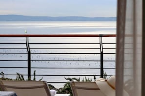 Un balcon offrant une vue sur une mer calme et des montagnes lointaines.