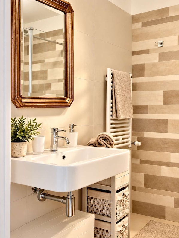 A bathroom with a white sink, a mirror, a towel rack, and a shower area.