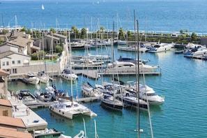 A marina with various boats docked, a waterfront building, and a clear view of the sea.