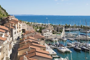 A coastal marina with boats docked, surrounded by terraced buildings with red-tiled roofs.