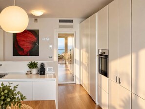 Une cuisine moderne avec des meubles blancs, un îlot central et un luminaire suspendu.