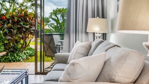 A modern living room with a grey sofa, a glass coffee table, and a lamp. - NEWLY Updated, Beachfront, WALK out to Beach, Pool, Hot Tub, BBQ! (Kihei)