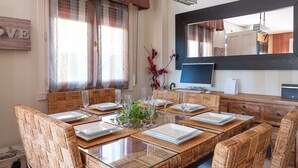 Comedor con una mesa de vidrio, sillas de mimbre y un espejo en la parte superior.