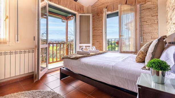 Un dormitorio con una cama grande, vistas al exterior y un balcón.