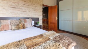 Un dormitorio con una cama grande, cabecera de madera, alfombra mullida y puerta corrediza de vidrio que da a un balcón.