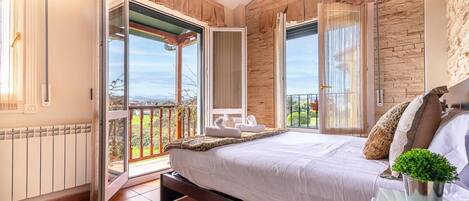 Ein Schlafzimmer mit einem großen Bett, Blick ins Freie und einem Balkon.