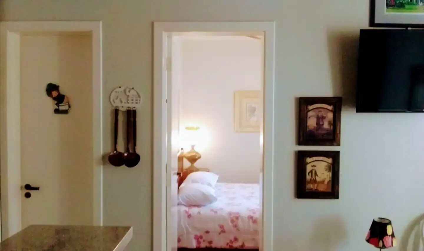 Habitació d'hotel amb un llit, televisió i una porta que condueix a una altra habitació.